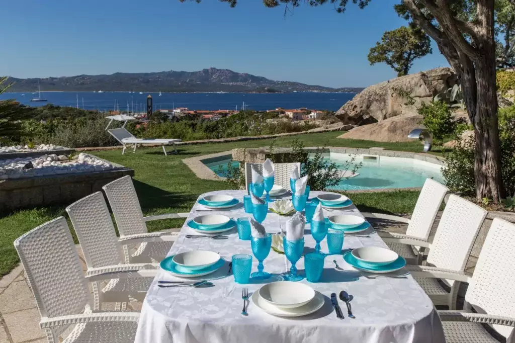 Tavola apparecchiata in turchese vicino alla piscina, con vista sul mare